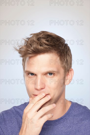 Portrait of man covering his mouth with hand. Photo : Rob Lewine