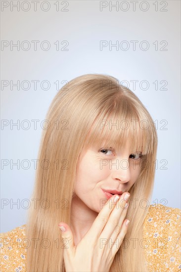Portrait of woman covering her mouth with hand. Photo : Rob Lewine