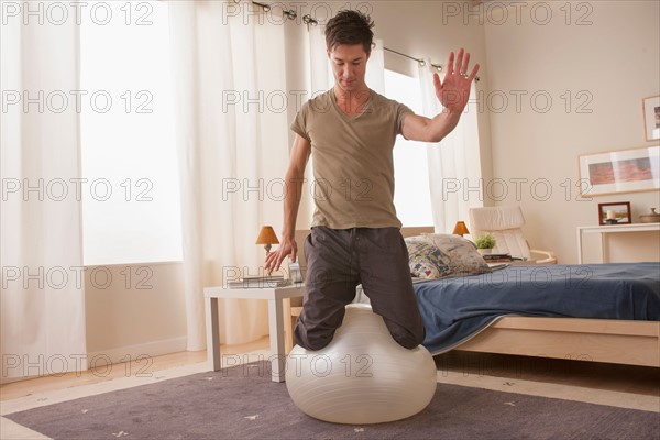 Man kneeling on top of fitness ball. Photo : Rob Lewine