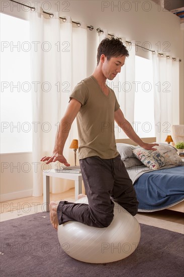 Man kneeling on top of fitness ball. Photo : Rob Lewine