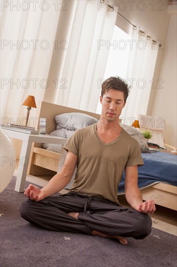 Man meditating on bedroom floor. Photo : Rob Lewine