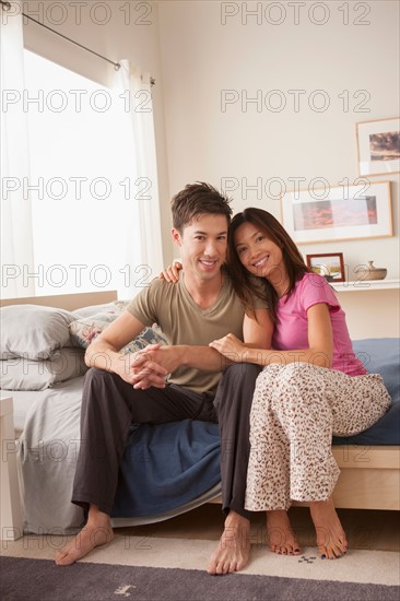 Portrait of couple sitting on bed. Photo : Rob Lewine