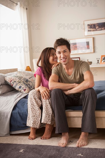 Smiling couple sitting on bed. Photo : Rob Lewine