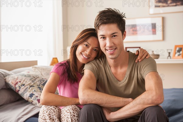 Portrait of couple sitting on bed. Photo : Rob Lewine