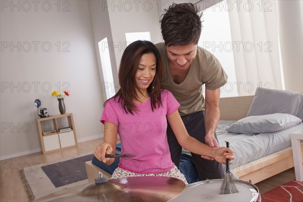 Man teaching woman how to play drums. Photo: Rob Lewine