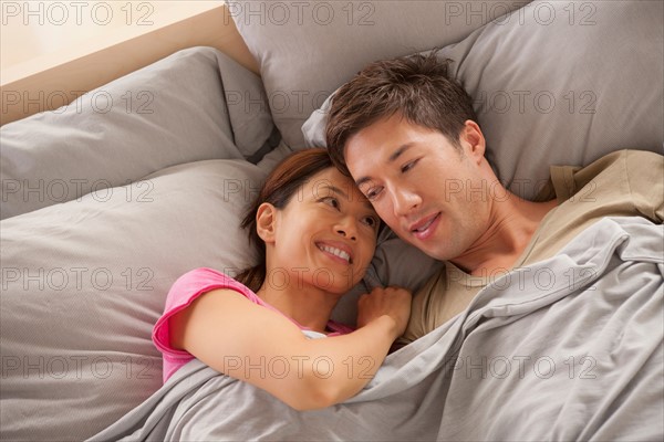 Portrait of couple lying in bed. Photo : Rob Lewine