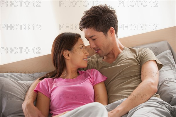 Couple sitting in bed with face to face. Photo : Rob Lewine