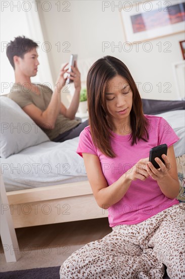 Couple using mobile phone and digital tablet. Photo : Rob Lewine