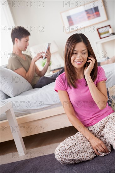 Couple using mobile phone and digital tablet. Photo : Rob Lewine