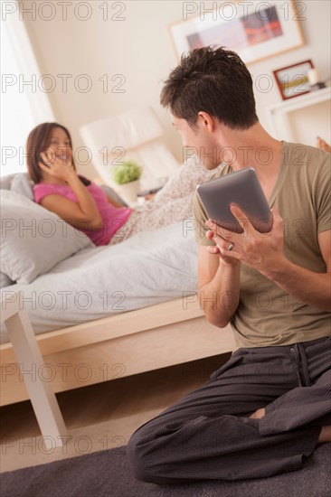 Couple using mobile phone and digital tablet. Photo: Rob Lewine