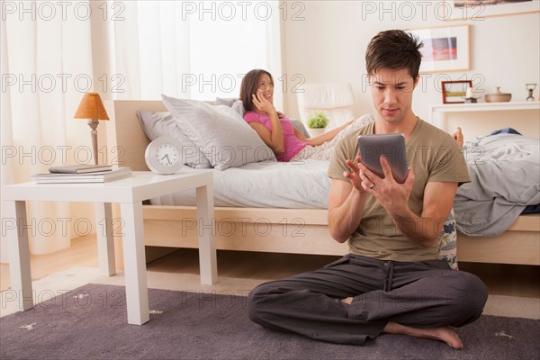 Couple using mobile phone and digital tablet. Photo: Rob Lewine