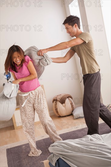 Couple having pillow fight in bedroom. Photo : Rob Lewine