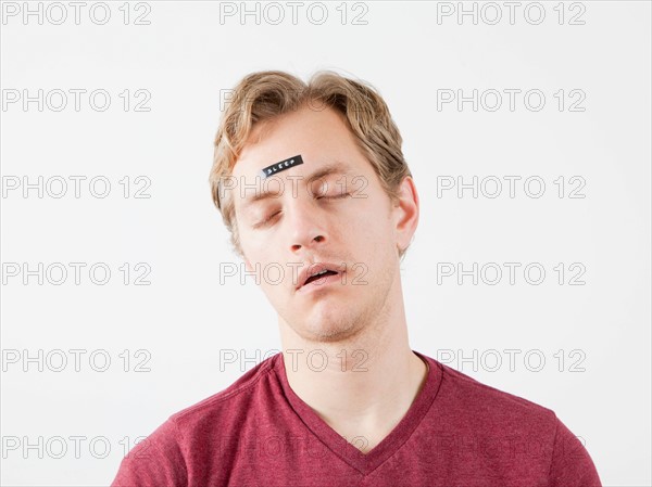 Sleeping man with sticker on his forehead. Photo : Jessica Peterson