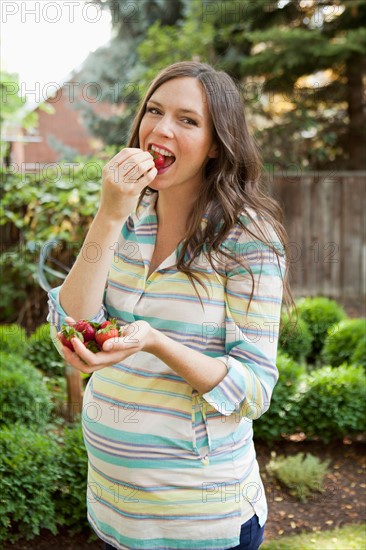 Portrait of pregnant mid adult woman eating strawberries. Photo: Jessica Peterson