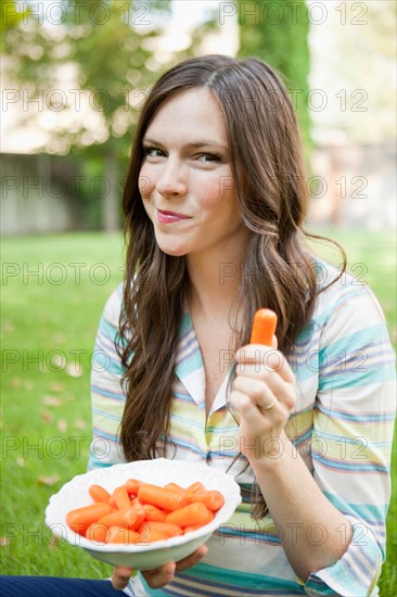 Portrait of mid adult woman eating carrots. Photo: Jessica Peterson