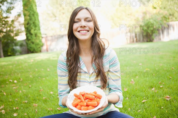 Portrait of mid adult woman eating carrots. Photo: Jessica Peterson