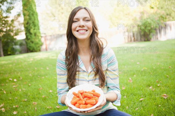 Portrait of mid adult woman eating carrots. Photo : Jessica Peterson