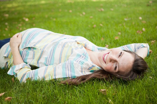 Portrait of pregnant mid adult woman laying down on grass. Photo: Jessica Peterson