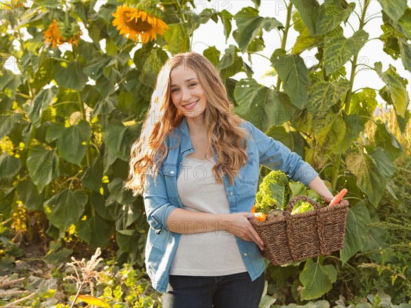 Portrait of young woman harvesting sunflowers. Photo : Jessica Peterson