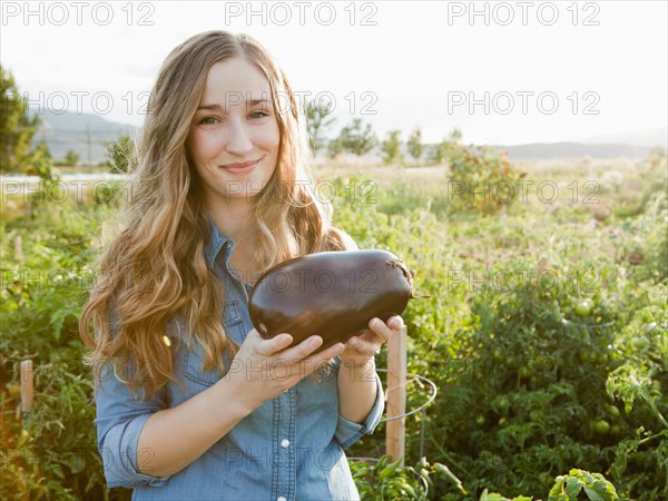 Portrait of young woman holding eggplant. Photo : Jessica Peterson