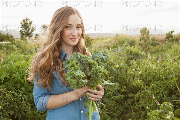 Portrait of young woman holding kale. Photo: Jessica Peterson