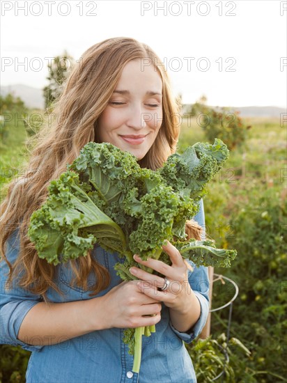 Portrait of young woman holding kale. Photo : Jessica Peterson