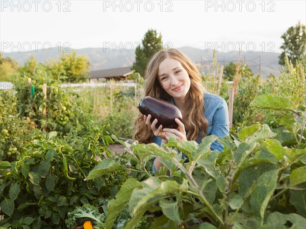 Portrait of young woman harvesting eggplant. Photo : Jessica Peterson