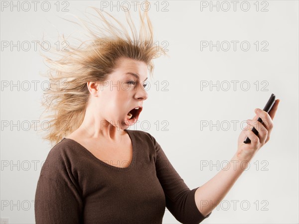 Studio shot of woman with windblown mouth holding phone. Photo: Jessica Peterson