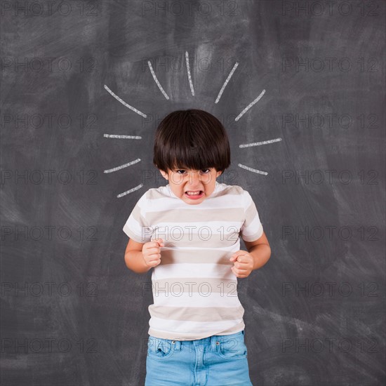 Studio portrait of boy (6-7) in front of blackboard. Photo : Jessica Peterson