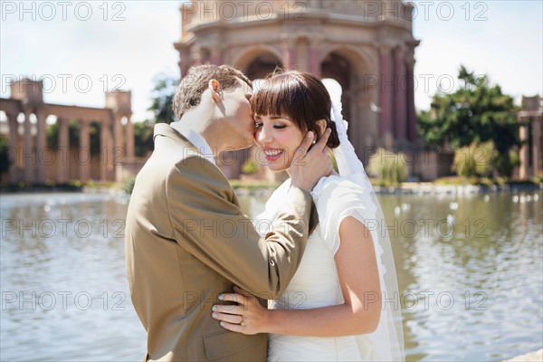 Groom kissing bride in park. Photo : Jessica Peterson