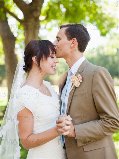 Groom kissing bride in park. Photo: Jessica Peterson