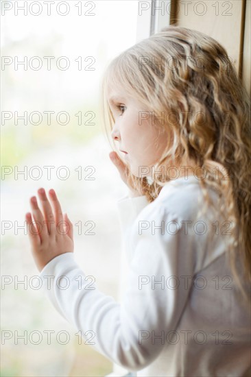 Girl (4-5) looking through window. Photo : Jessica Peterson