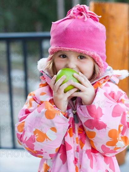 Girl (4-5) wearing warm clothing eating outdoors. Photo: Jessica Peterson