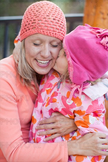 Daughter (4-5) kissing mother outdoors. Photo: Jessica Peterson