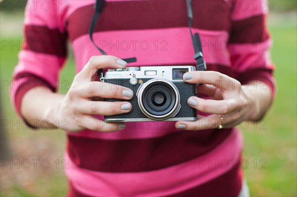 Midsection of woman holding old camera. Photo : Jessica Peterson