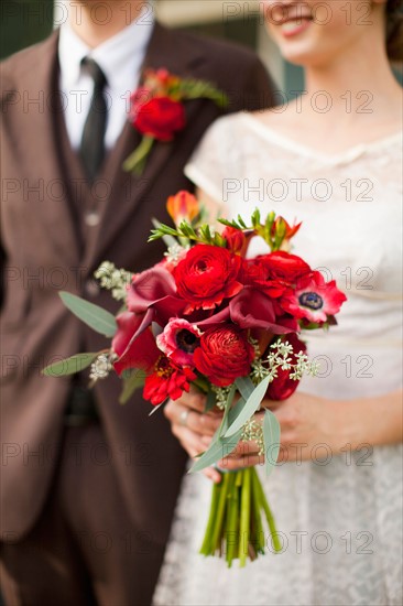 Mid section of wedding couple with bouquet in focus. Photo: Jessica Peterson