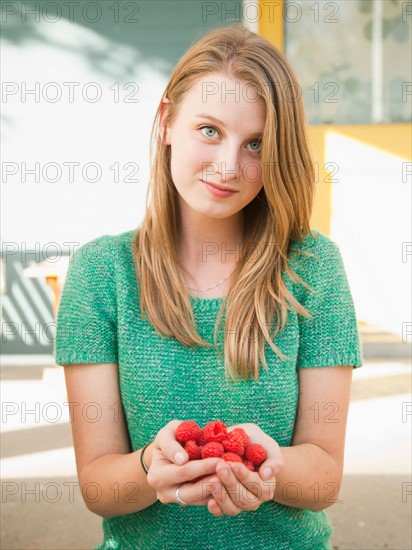 Portrait of young woman holding raspberries. Photo: Jessica Peterson