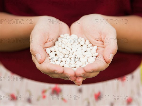 Mid-section of woman holding white beans. Photo : Jessica Peterson