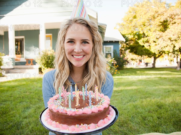 Portrait of young woman holding birthday cake. Photo : Jessica Peterson