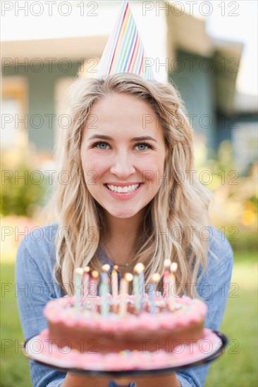 Portrait of young woman holding birthday cake. Photo: Jessica Peterson
