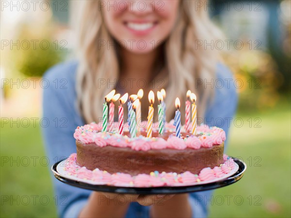 Mid-section of young woman holding birthday cake. Photo : Jessica Peterson