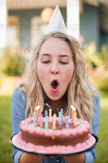 Portrait of young woman blowing birthday candles. Photo: Jessica Peterson