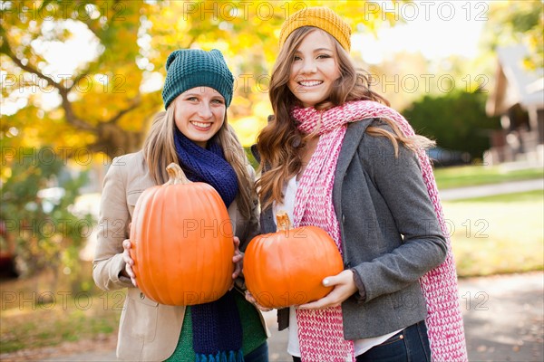 Portrait of two young women holding pumpkins. Photo: Jessica Peterson