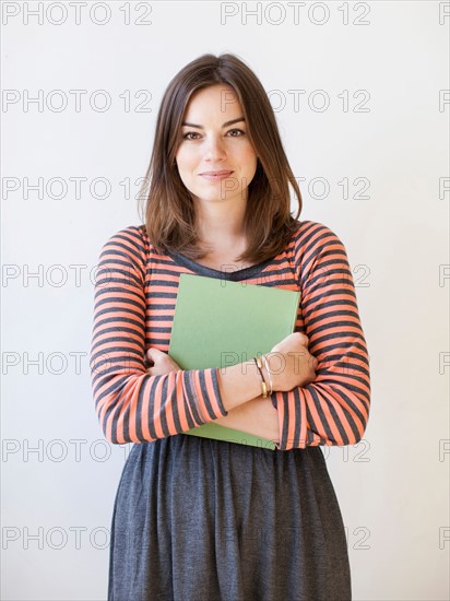 Studio shot portrait of young woman holding book. Photo: Jessica Peterson