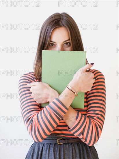 Studio shot portrait of young woman holding book. Photo : Jessica Peterson