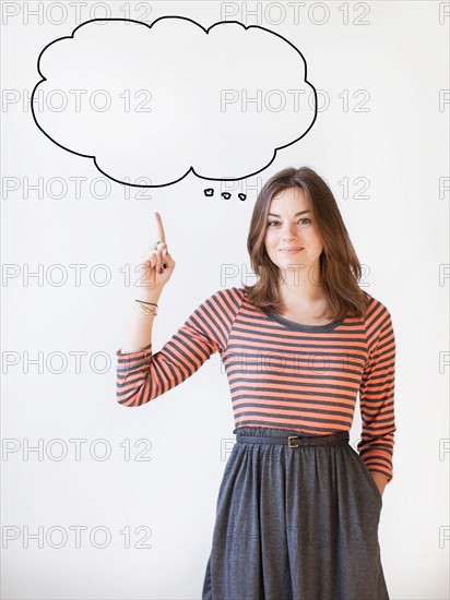 Studio shot young woman pointing up on thought bubble. Photo: Jessica Peterson