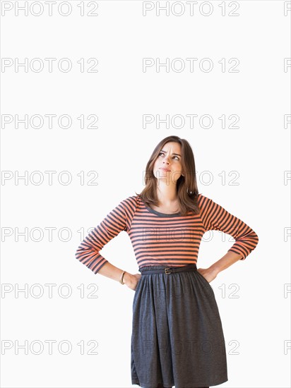 Studio shot young woman with hands on hip looking up . Photo : Jessica Peterson