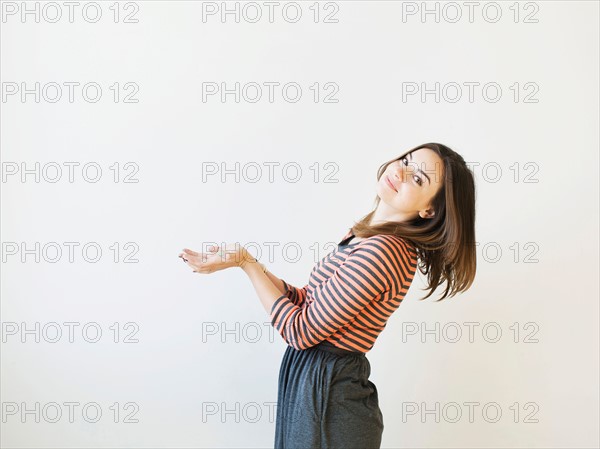 Studio shot young woman bending over backwards pretending like holding something. Photo : Jessica Peterson