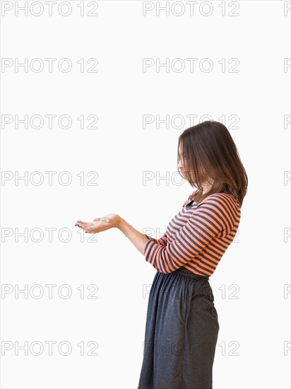 Studio shot young woman bending over backwards pretending like holding something. Photo : Jessica Peterson