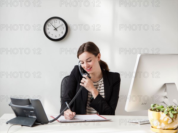 Studio shot of young woman working in office talking on phone . Photo: Jessica Peterson